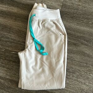 Figs khaki colored scrub pants with teal strings. XS/R